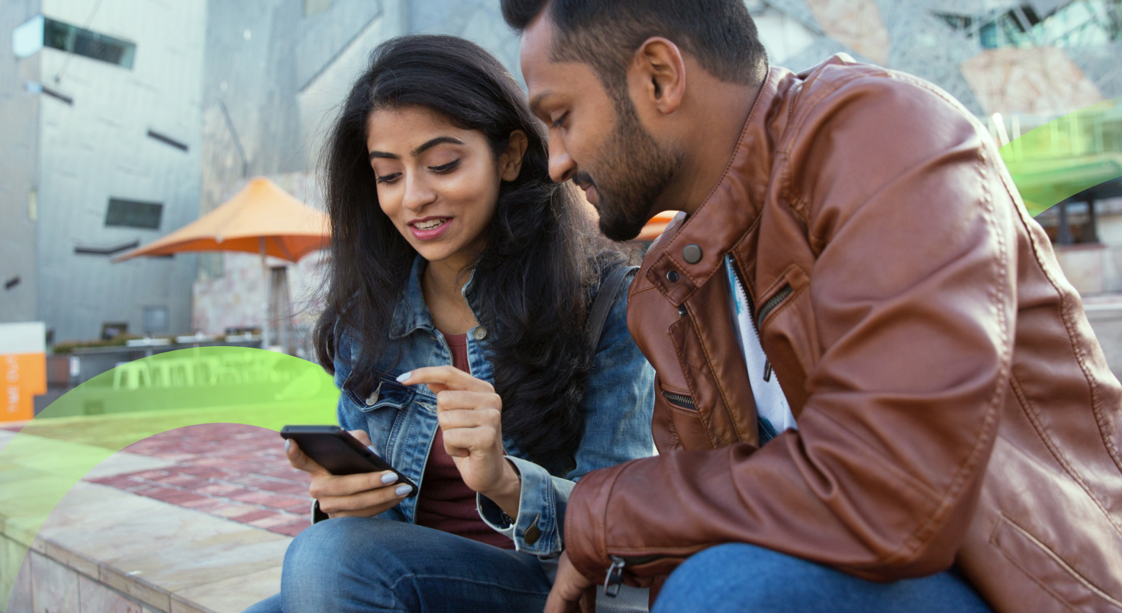 Two people sitting looking over one phone