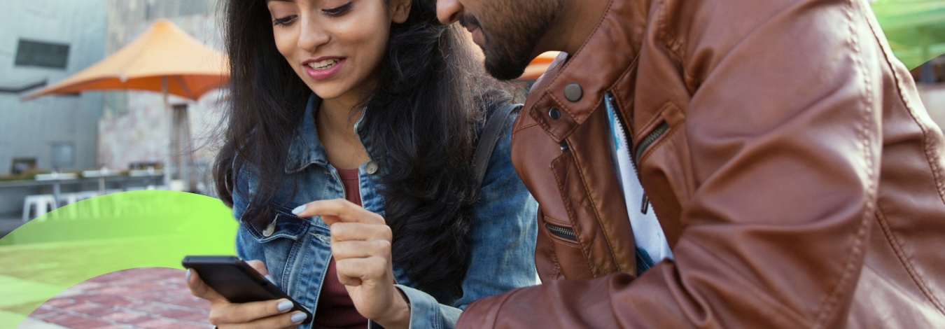 Two people sitting looking over one phone