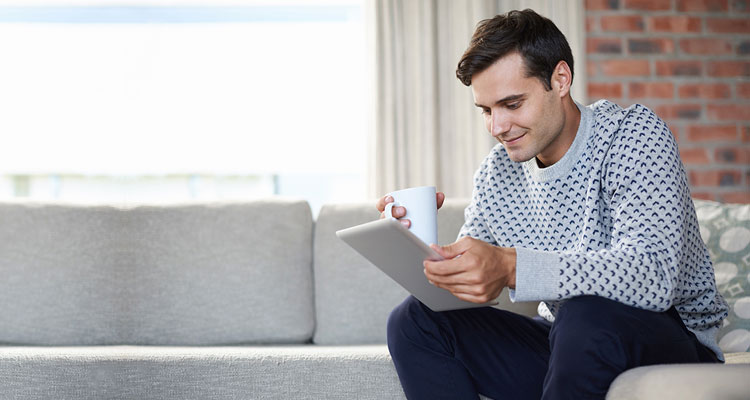 Man looking at tablet device sitting on a couch